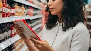 קונה בודקת את סימון ההכשר על אריזת מוצר במדף סופרמרקט בניו יורק